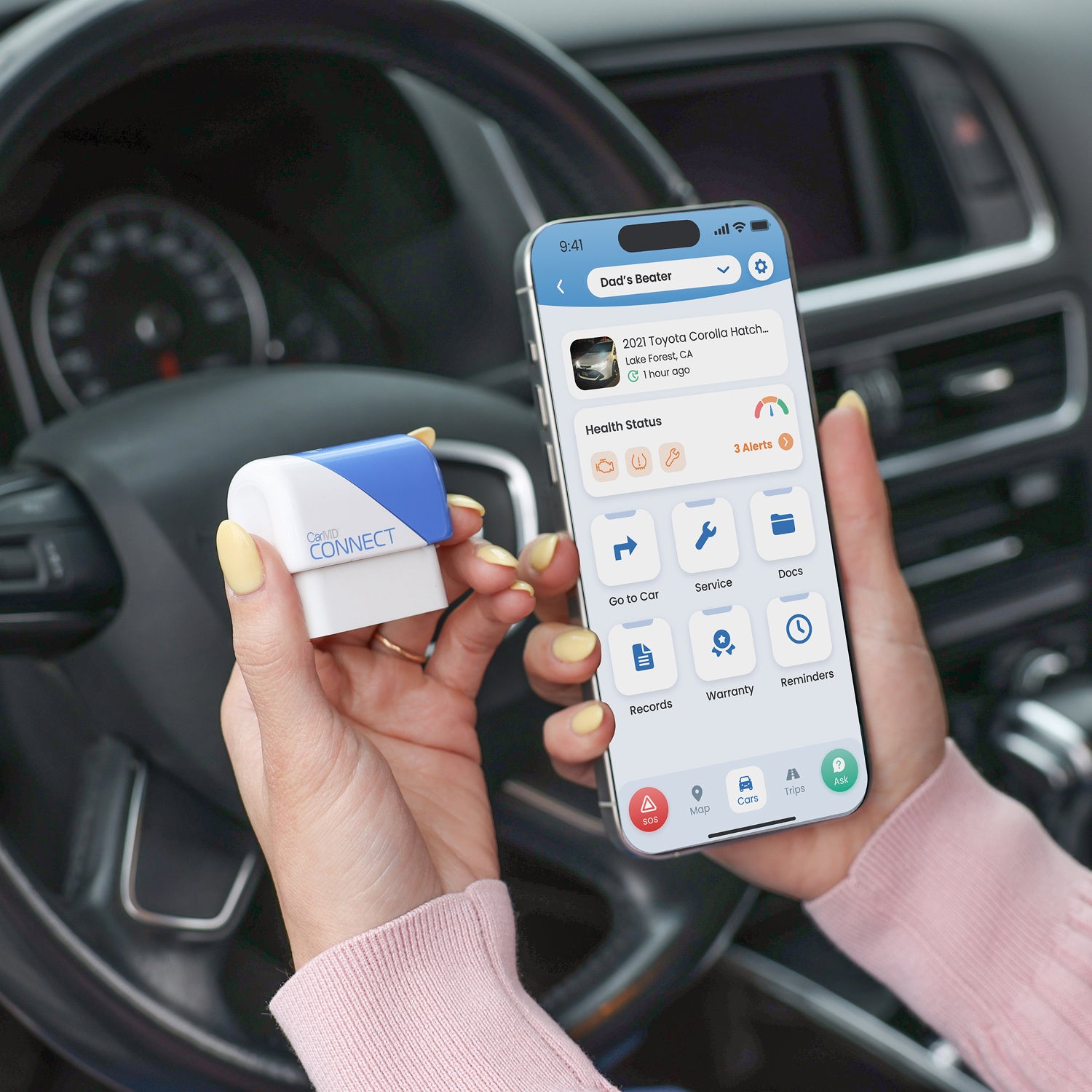 CarMD Connect dongle and phone showing the CarMD Connect app paired inside a vehicle