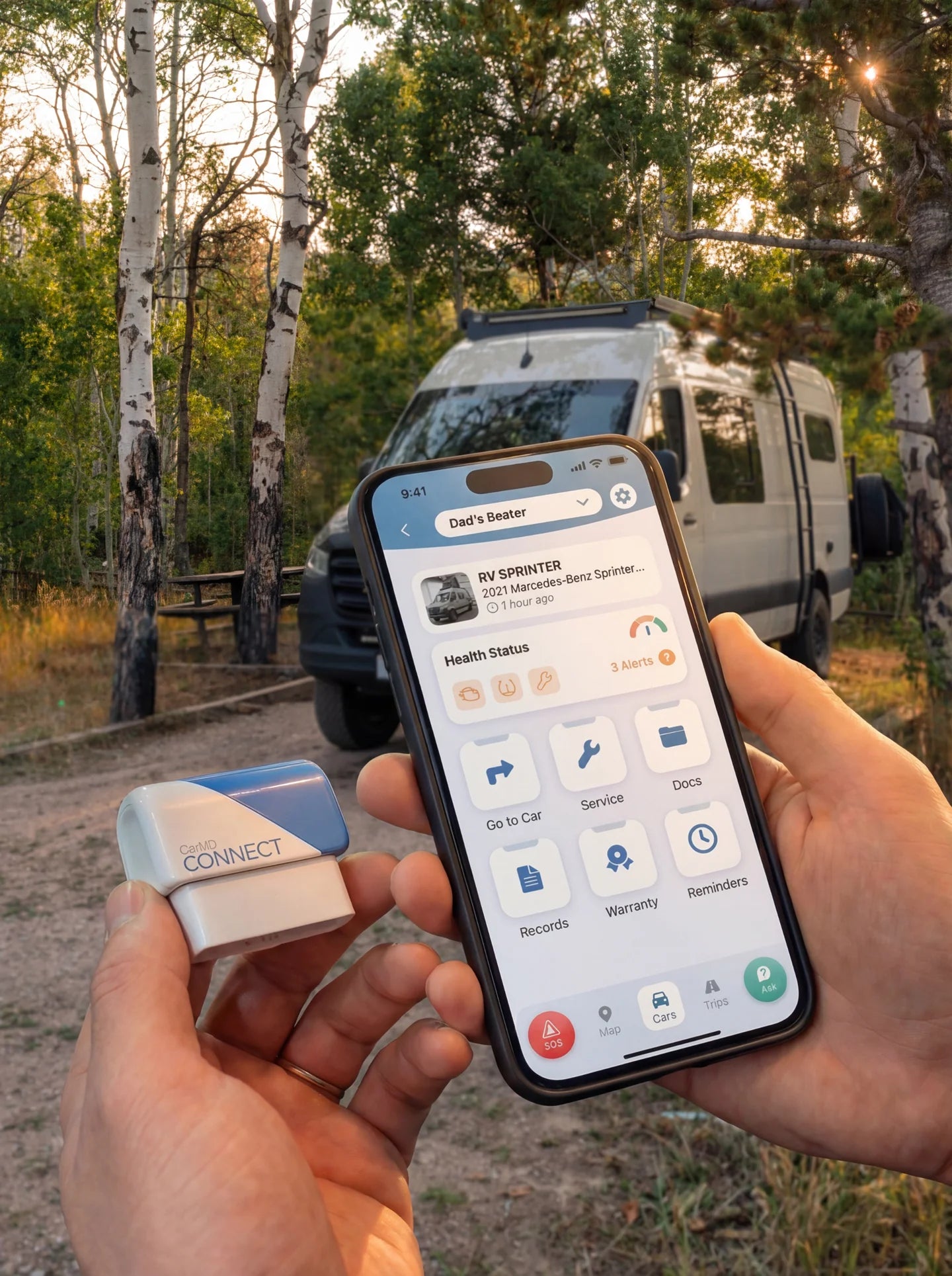 CarMD Connect OBD2 dongle held with phone showing diagnostic app